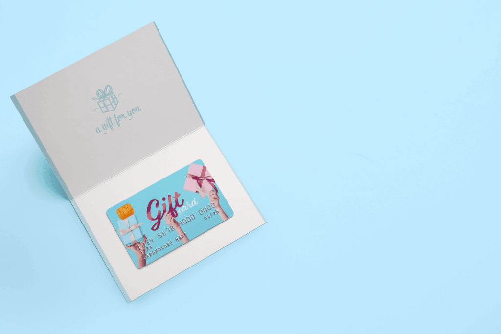 An open card displaying a blue gift card with pink and blue present illustrations inside.