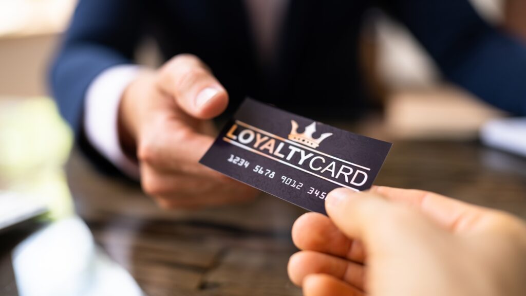 Close-up of two people exchanging a loyalty card over a wooden table