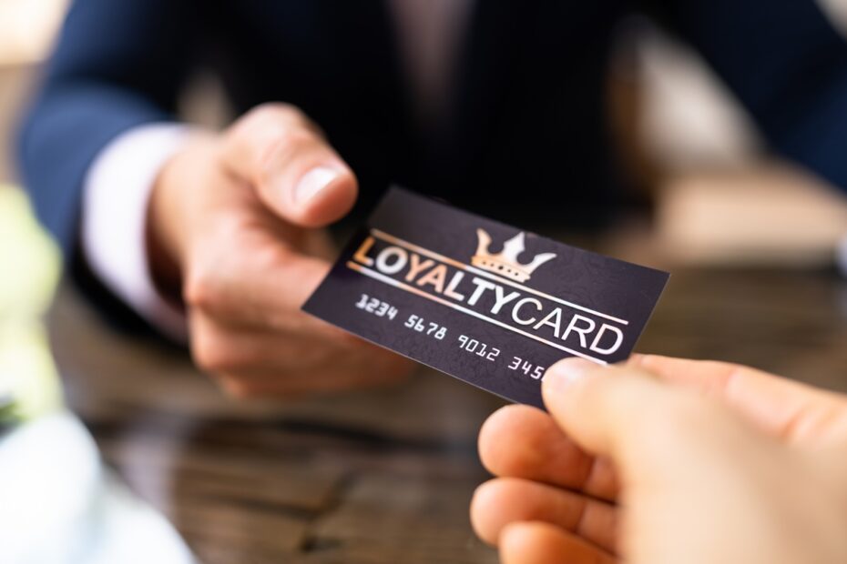 Close-up of two people exchanging a loyalty card over a wooden table