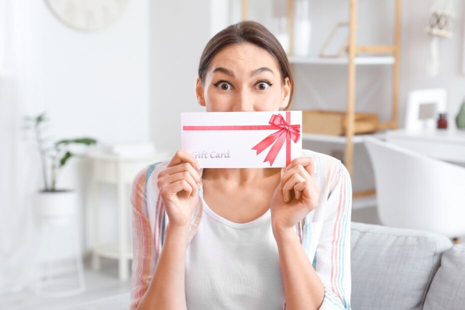 Woman holding a gift card envelope with a pink ribbon, in a bright room