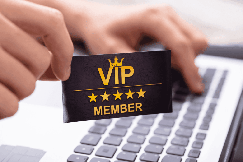 A person holding a black VIP membership card with gold text and stars above a laptop keyboard
