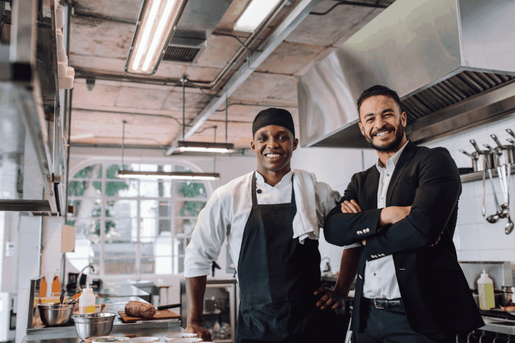 Chef and manager smiling in a professional kitchen.