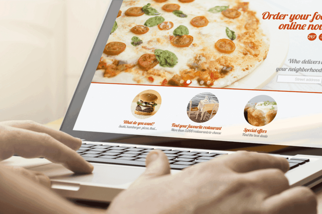Person browsing an online food delivery website on a laptop, with a pizza image and menu options visible.