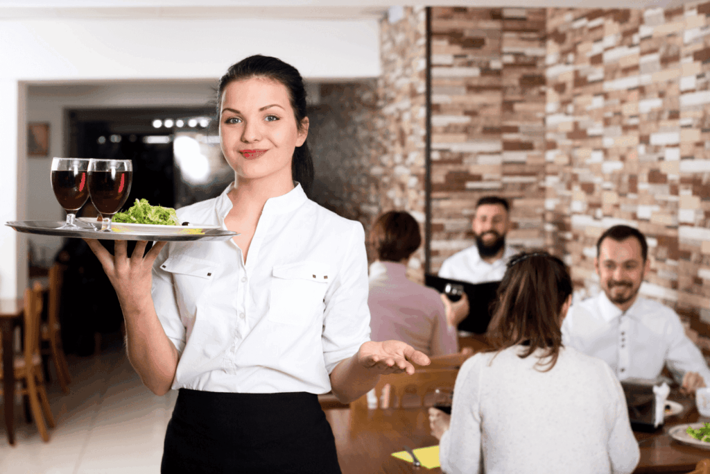 Smiling waitress serving food and drinks in a restaurant