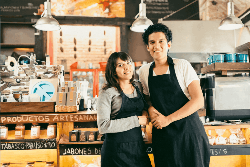 Two employees smiling behind a counter in a rustic shop.