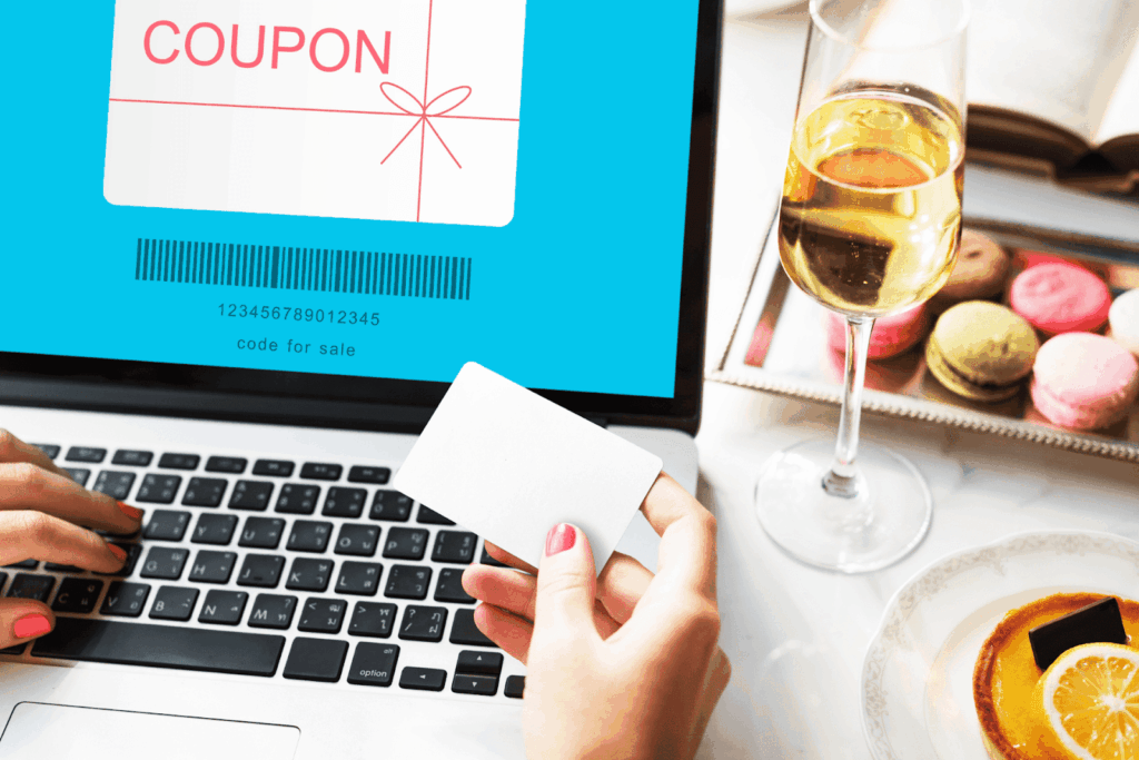 A person holding a blank card while shopping online with a digital coupon displayed on a laptop screen.