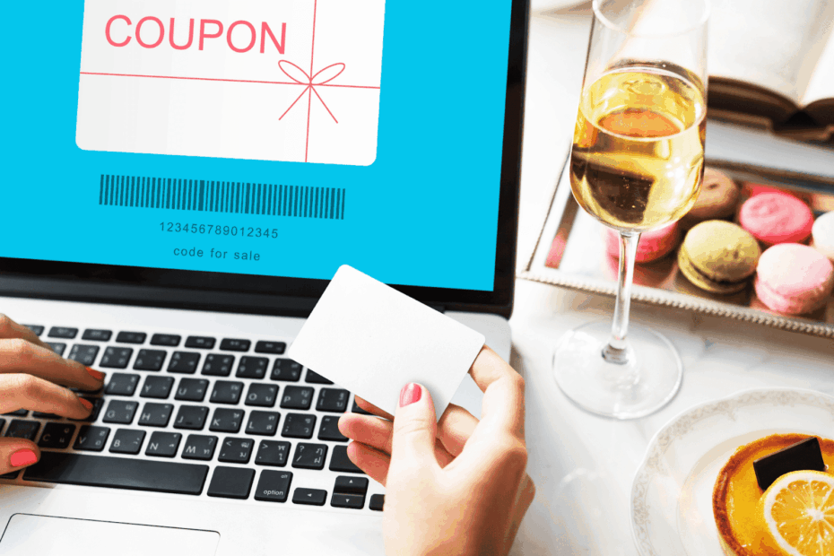 A person holding a blank card while shopping online with a digital coupon displayed on a laptop screen.