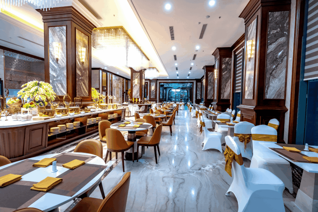 A bright, elegant dining hall with neatly arranged tables and a buffet area.