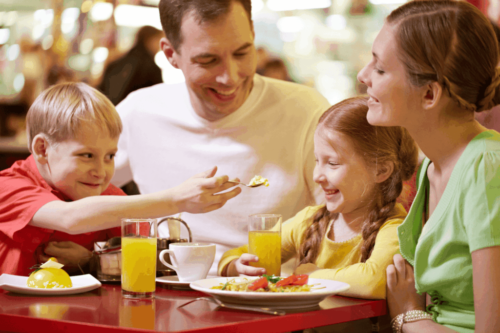  A family with two children enjoying a meal together at a restaurant table.