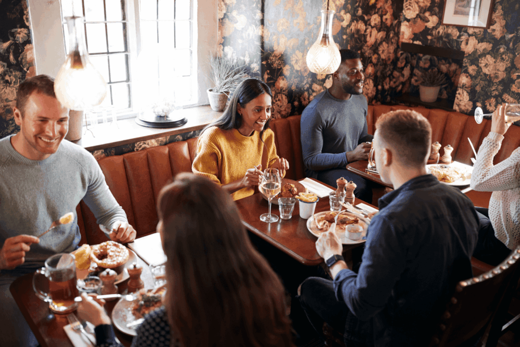 A group of friends enjoying a meal and conversation in a cozy restaurant booth.