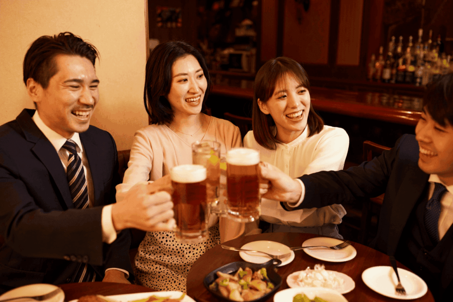 Friends in business attire raising beer mugs in a celebratory toast at a restaurant.