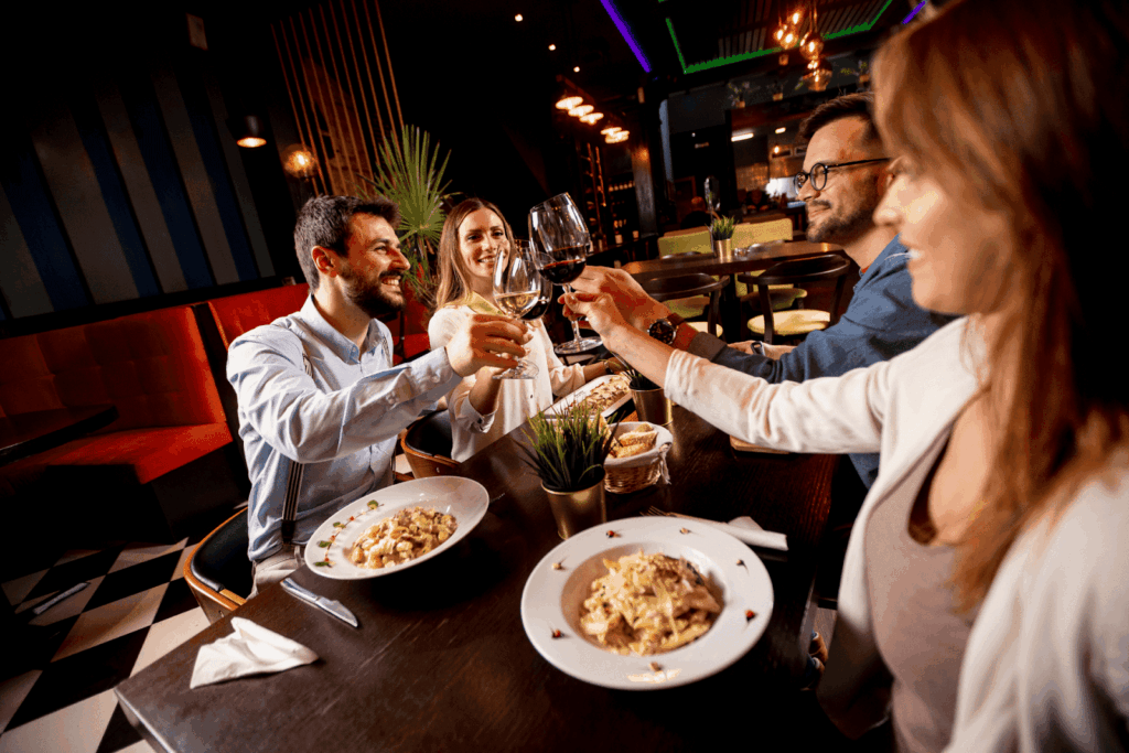 Friends raising wine glasses in a toast while dining at a restaurant.