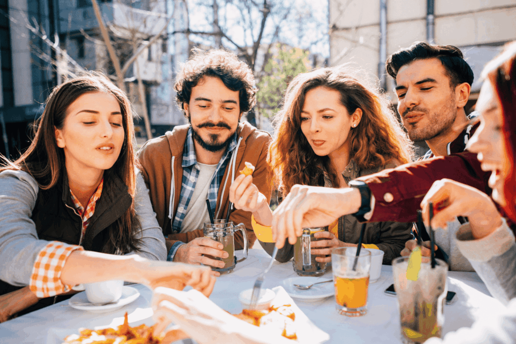 Friends sitting outdoors sharing snacks and drinks on a sunny day.