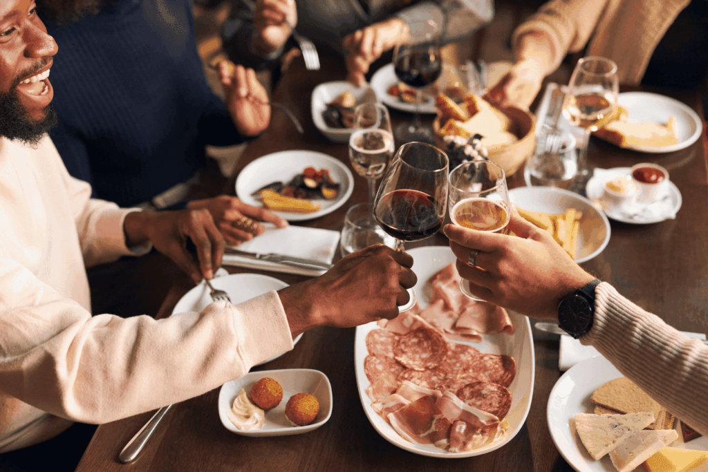 Friends toasting with wine over a table of shared dishes.