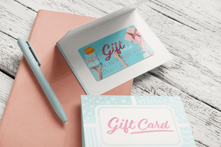 Gift card displayed inside an open card on a desk with a pen and notebook.