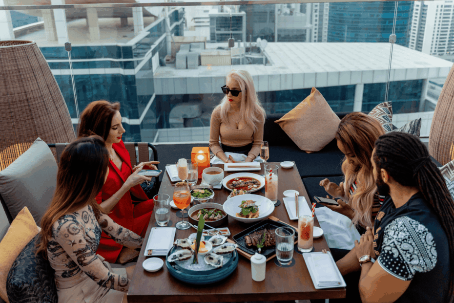Group of friends dining together on a rooftop terrace with city views.