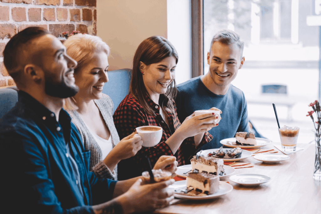 Group of friends enjoying coffee and dessert together at a café.