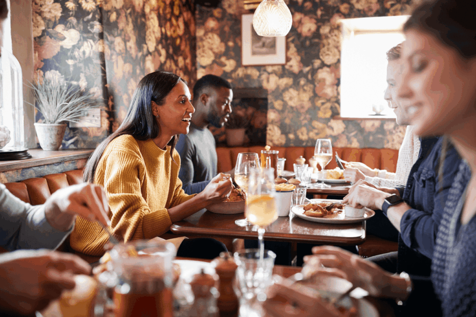 Group of friends enjoying food and conversation at a cozy restaurant table.