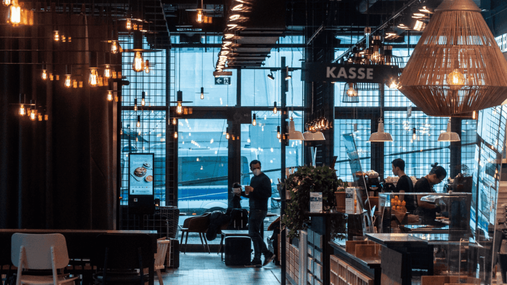 Interior of a modern café with warm lighting and people near the counter.