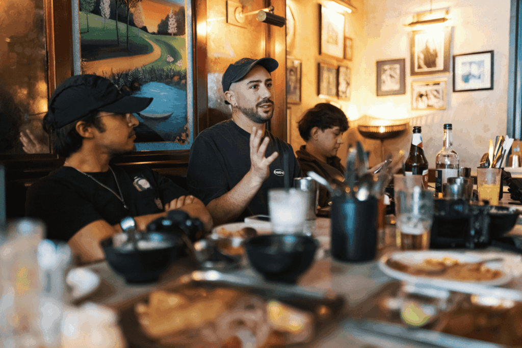 People sitting at a restaurant table talking, with food and drinks in front of them.