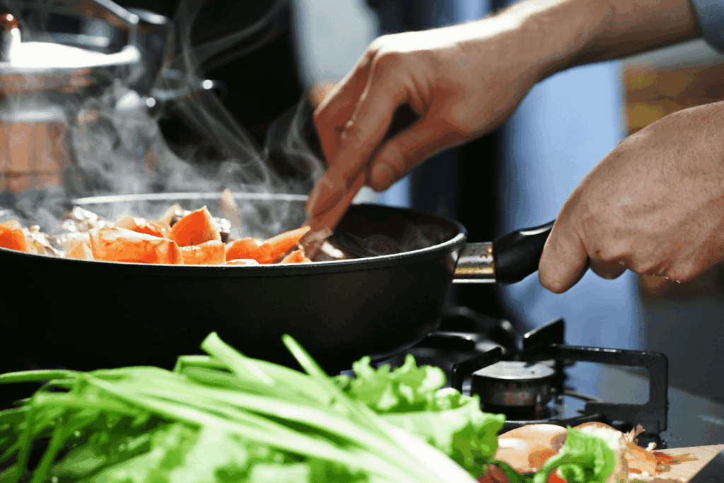Person cooking vegetables in a steaming pan on a stove
