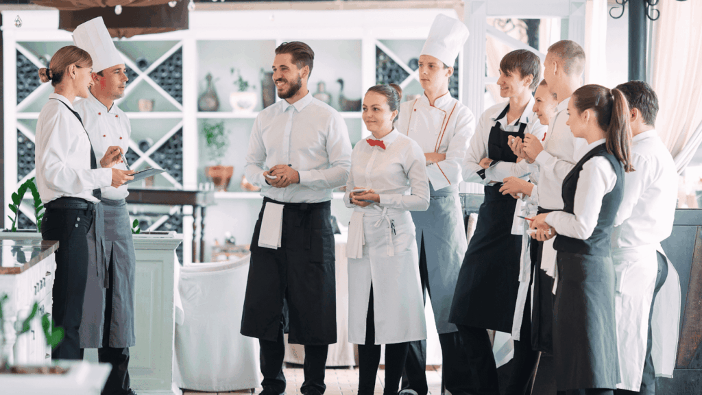Restaurant staff gathered in a group receiving instructions before service.