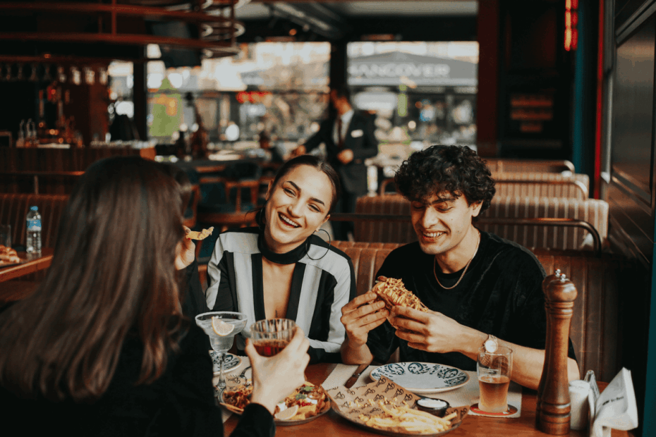 Three friends enjoying food and drinks together in a cozy restaurant.