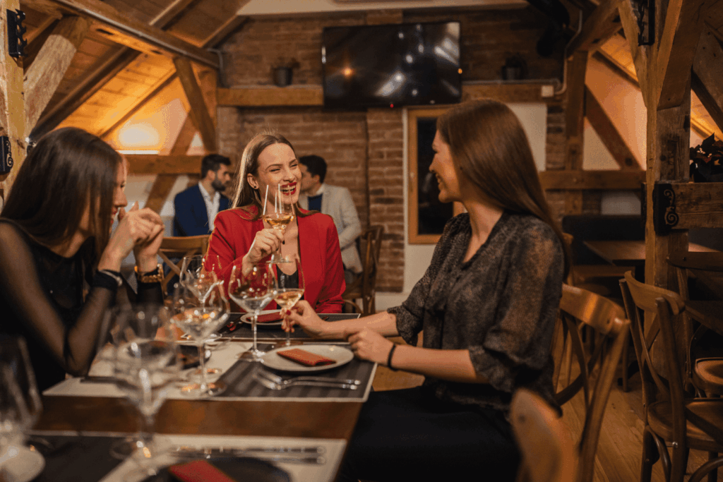 Three women enjoying wine and conversation at a cozy restaurant table.